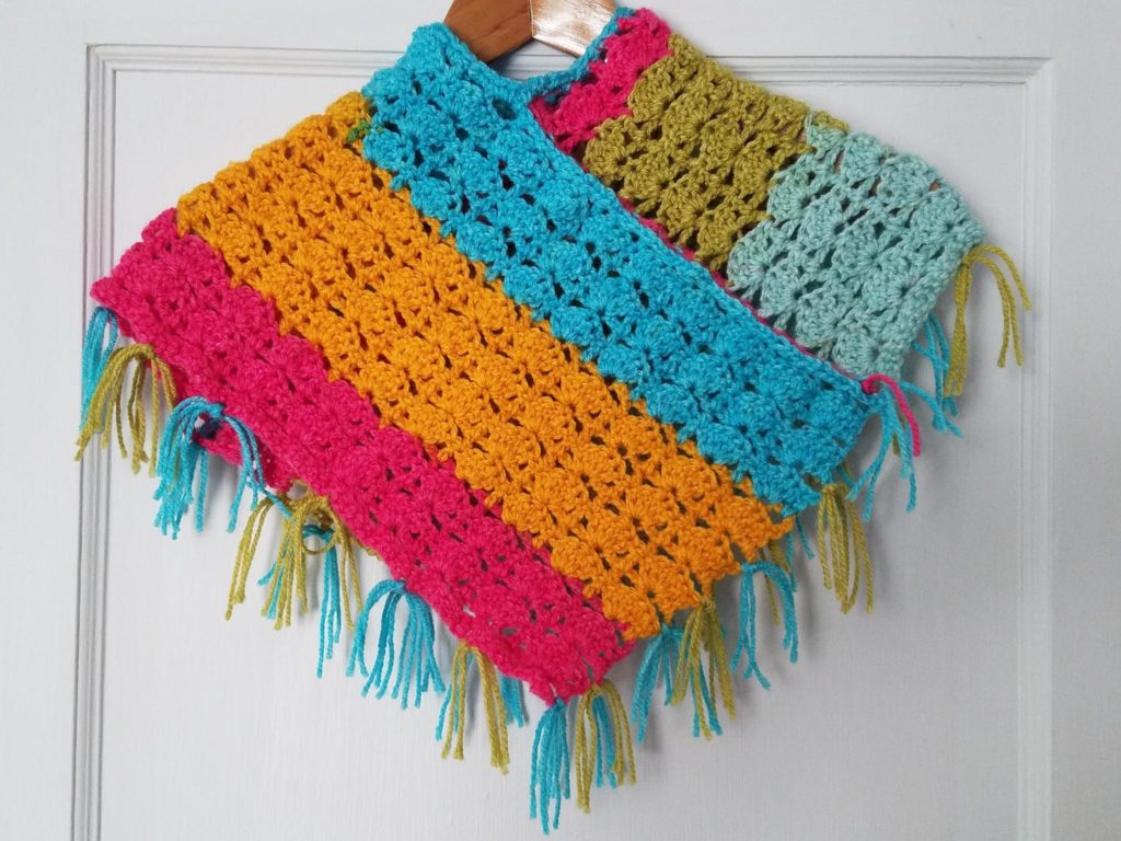 Colorful crocheted poncho hanging on a door