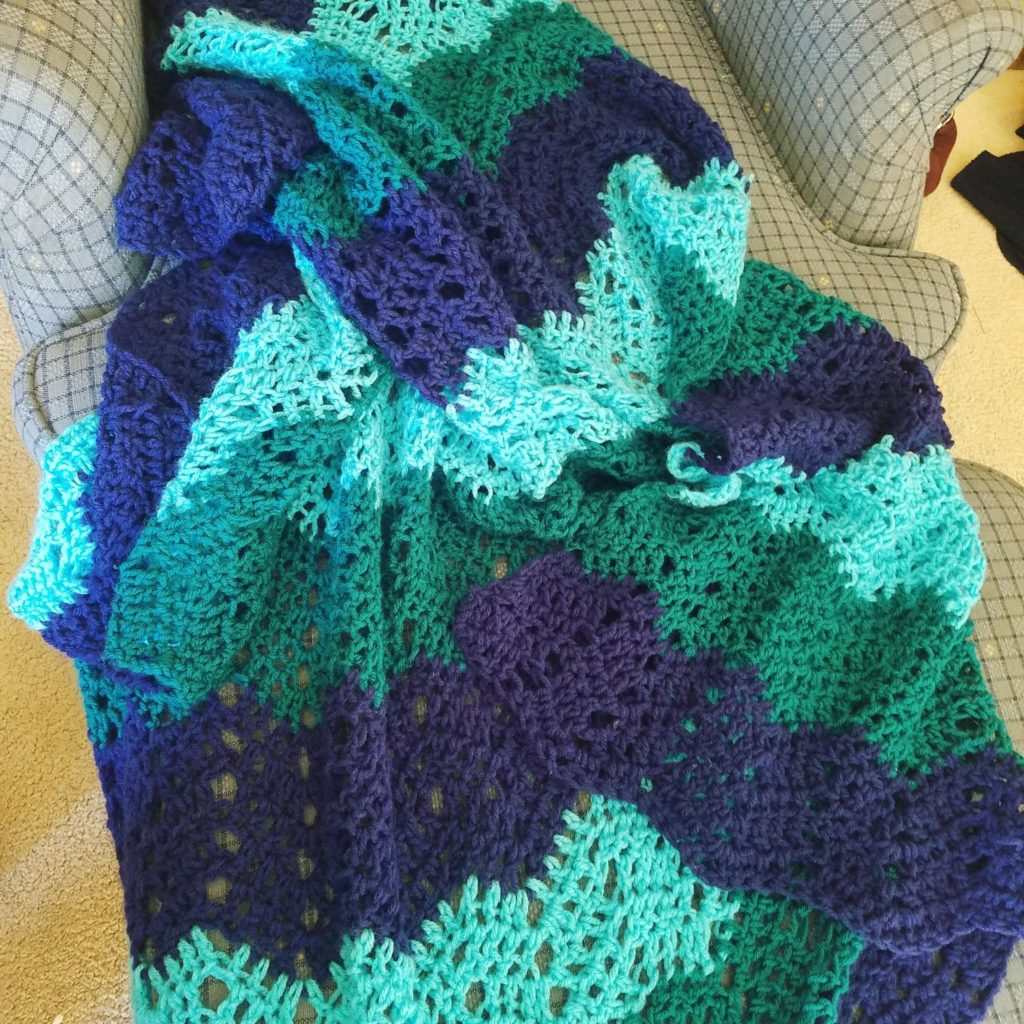 Green and blue striped crochet blanket on a chair