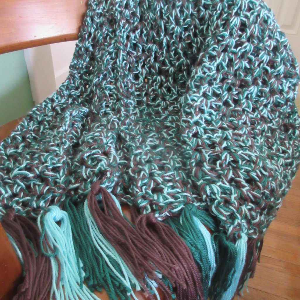 Green and brown crocheted blanket on a chair