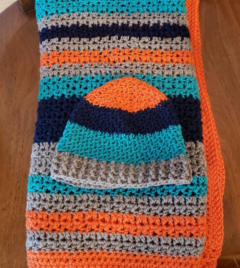 Crocheted orange and blue striped baby blanket and hat